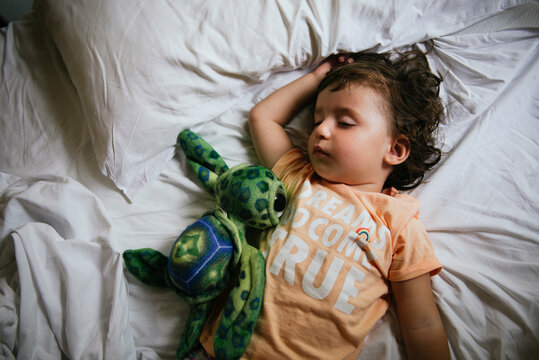 Baby girl sleeping on bed with t-shirt message 'Dreams do come true'
