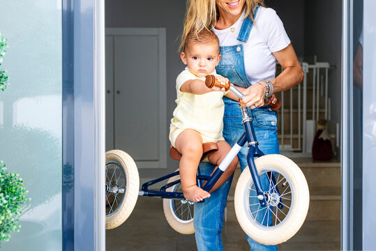 Mother playing with son sitting on tricycle at home