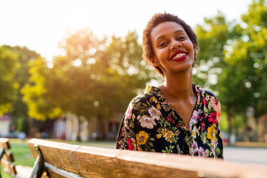 Portrait of smiling young woman on bench in a park
