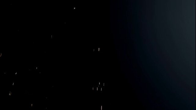 A video showcasing a large amount of sand falling down against a dark background