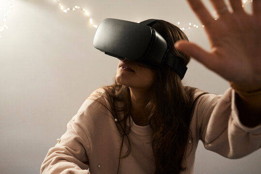 Young woman using VR headsets playing games on the sofa at home at night