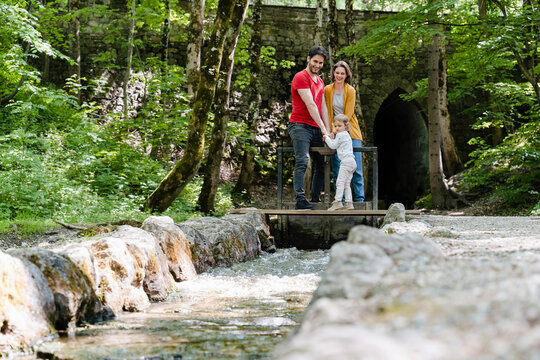 Parents with daughter looking at dam while standing in forest