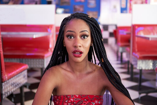 Portrait of a young woman with braided hairstyle in an american diner restaurant