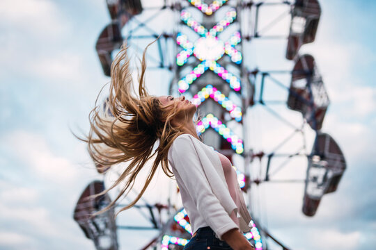 Long-haired young woman shaking her hair on a funfair