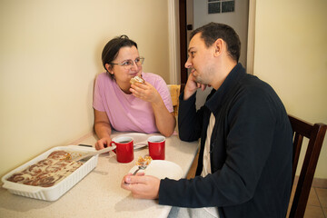 Caucasian male and female adults enjoying cinnamon rolls and coffee at home