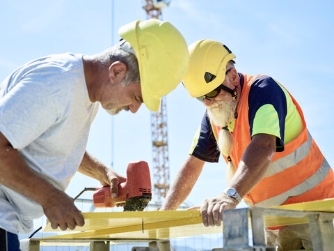 Construction worker cutting plywood with jigsaw on construction site