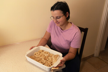 Female adult preparing homemade cinnamon rolls in kitchen