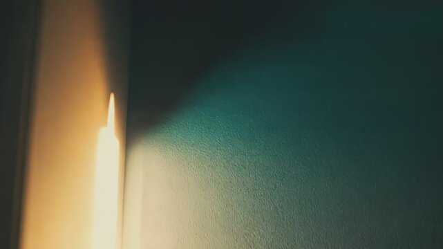 Warm sunlight beam pierces a dark room through an open door, casting golden glow on the threshold symbol of hope, new beginnings, opportunity and quiet discovery
