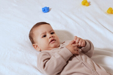 Happy newborn baby makes a funny face. Portrait of a crawling baby in his room close up