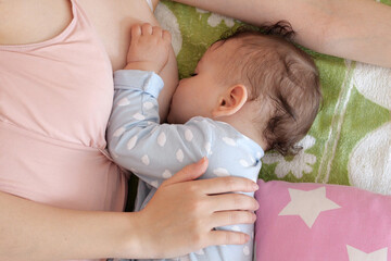 Young woman breastfeeding her baby at home. Milk from mother's breast is a natural medicine to baby. Mother day bonding concept with newborn baby nursing