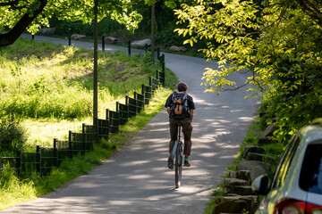 Unicyclist riding through a peaceful green park on a paved path. Sustainable mobility, unique urban transport, healthy lifestyle, balance skills, and nature connection. © Anna