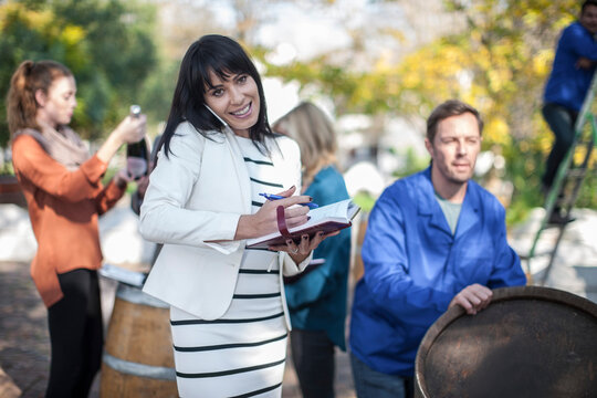 Wine saleswoman with group of clients outdoors and wine worker with barrel
