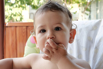 Portrait of little baby boy eating food. Baby with a spoon in feeding chair. Cute baby eating first meal