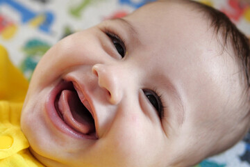 Happy newborn baby makes a funny face. Portrait of a crawling baby in his room close up