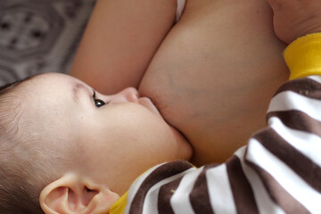 Young woman breastfeeding her baby at home. Milk from mother's breast is a natural medicine to baby. Mother day bonding concept with newborn baby nursing