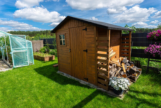 A wooden garden shed standing very close to the property fence.
