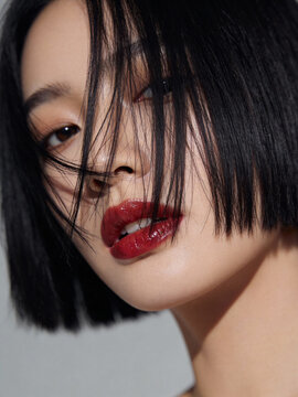 A young woman with bob-cut hair, the hair falling down close to all her face till slightly below her nose. Soft Defiance in a Fragmented Look