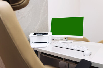 Fototapeta premium Modern home office workspace. Desktop computer with green screen monitor. White desk with printer and keyboard. Minimal interior design. Clean workplace setup with copy space.