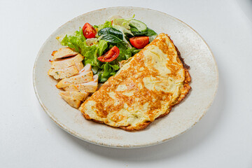 Savory omelette accompanied by a vibrant salad of fresh greens and juicy tomatoes