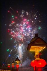 Colorful fireworks burst across the night sky, filling it with light, smoke, and celebration.