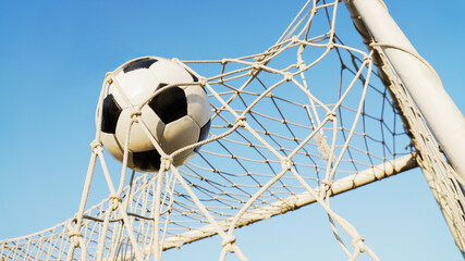 Soccer ball inside the goalpost net with blue sky background, concept of target and success