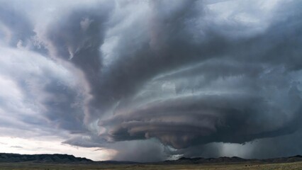 Fototapeta premium Massive spiral supercell thunderstorm looms over open plains under overcast skies.