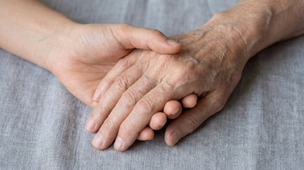 Fototapeta premium Young hand holding elderly wrinkled hand close up family support aging care love generation bridge background copy space help senior assistance