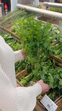Woman choosing fresh herbs at supermarket produce section