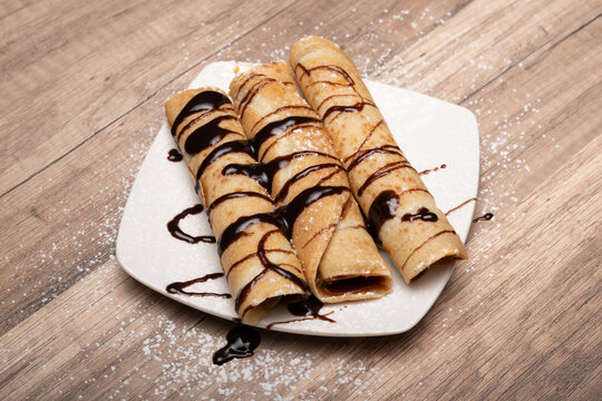 Crepes rellenos con salsa de chocolate sobre plato blanco