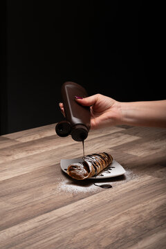 crepe o panqueque relleno con manjar, espolvoreado con az&uacute;car flor y ba&ntilde;ado en salsa de chocolate con la mano