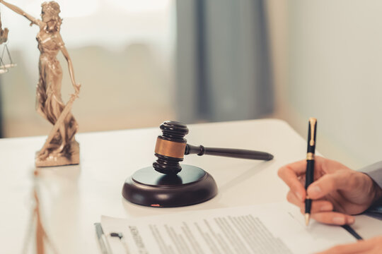 The close-up image shows a lawyer sitting in his office, with a small gavel for striking the judge's desk in court and a scale of justice on his desk.