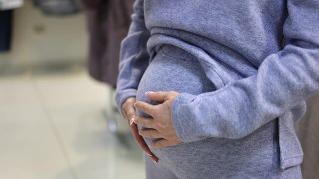 Pregnant woman. Touching her belly. Clothing store. Slow motion video.High quality 4k footage