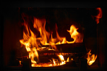 Obraz premium Fire burns in a fireplace during the evening, creating warmth and light in a cozy indoor space