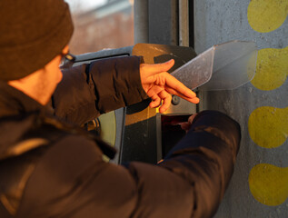 Fototapeta premium Man inserting money into a self service car wash machine and washing a car during sunset. Vehicle covered with foam and water spray, outdoor cleaning, winter weather, car care and maintenance concept.