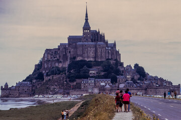 Mont-Saint-Michel, Normandy, France, August 1973: tourists walking along the historic causeway...