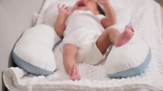Newborn baby kicking legs on pillow. Represents growth, physical development, and healthy early movement.