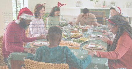 Obraz premium Holding hands, eight people bowing heads in dining room, with green tablecloth and Santa hats
