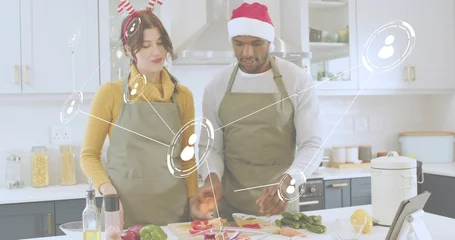 Selbstklebende Fototapeten Zu Kochen Slicing produce, olive-aproned couple with holiday hats preparing on kitchen island with board  © vectorfusionart