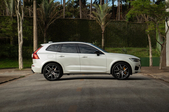 White Volvo XC60 Polestar side profile view, Luxury performance SUV parked on asphalt with trees
