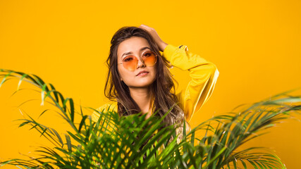 Naklejka premium Stylish portrait of a teenager wearing yellow glasses on a yellow background