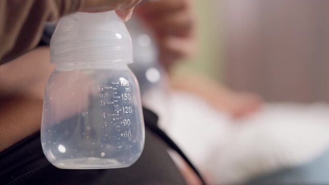 Close up of breastfeeding mom using electric pump with baby resting. Represents love, bonding, and natural nutrition.