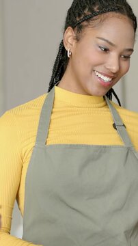 Vertical video: Smiling barista in olive apron taking phone tap payment at counter with reader
