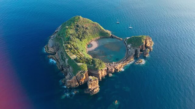 Ring-shaped volcanic islet with turquoise lagoon and steep cliffs off the coast of Sao Miguel, Azores, aerial view