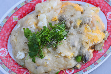 Soft oyster omelet topped with cilantro on a patterned plate.