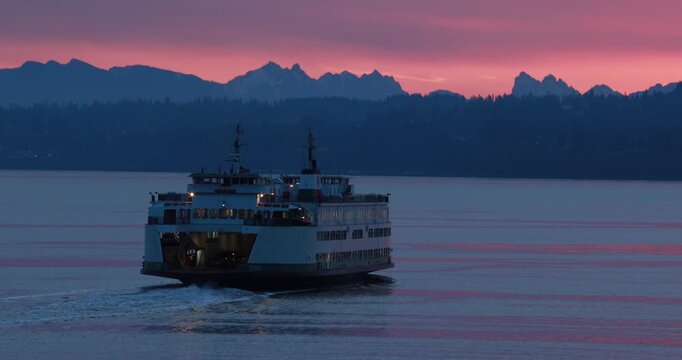 Ferry at sea at sunset. Washington state ferry in Puget sound with a pink sky over the Cascade mountain range in the background.