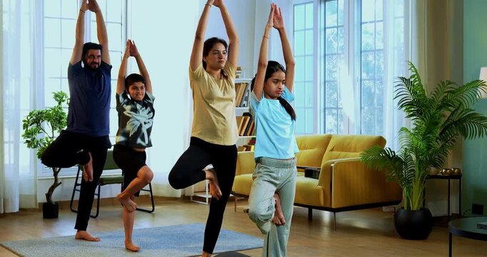 Indian family doing parvatasana yoga at home practicing mountain pose together indoors for healthy body and calm mind during morning routine inside a modern lavish living space