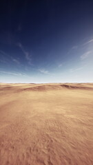 Fototapeta premium A vast desert stretches across the horizon, featuring gentle sandy dunes illuminated by sunlight. The clouds above create a serene atmosphere during midday.