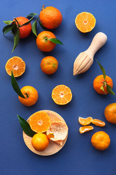 Fresh mandarin oranges and wooden juicer on blue background