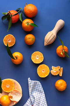 Fresh mandarins with juicer on blue background