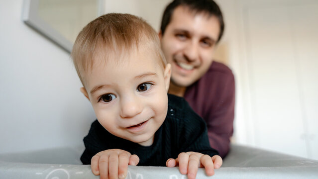Baby crawling at home with smiling parent behind